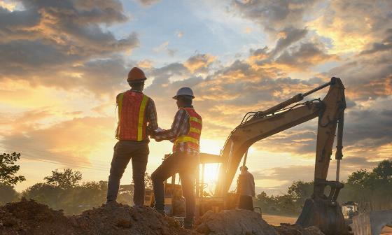 construction workers discussing project progress at sunset heavy machinery in background teamwork important steps for building