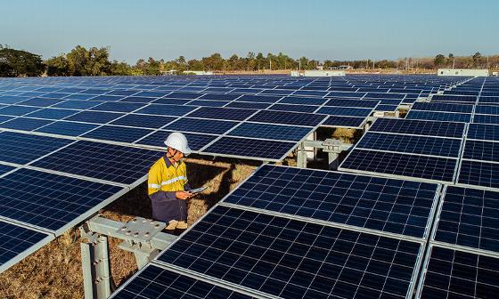 aerial view of a solar farm with rows of solar panels and a small structure surrounded by dirt and machinery highlighting renewable energy solutions for future technology