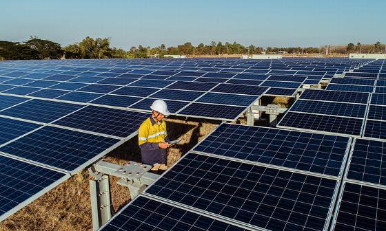 person in safety gear working among solar panels in a large solar farm showcasing renewable energy technology and sustainable solutions